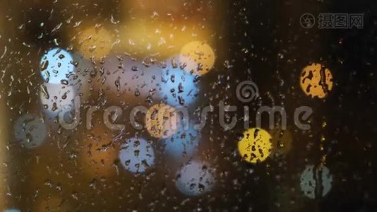 在晚上，窗外模糊的光斑和落在玻璃上的雨滴的特写。 概念视频