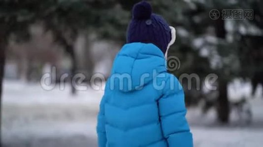 穿着蓝色冬装的可爱的四岁男孩走在雪地里视频