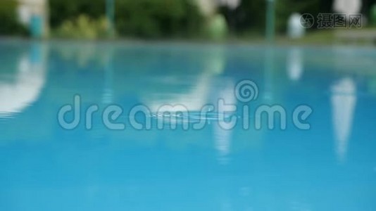 雨滴缓慢地落在游泳池的表面。 雨溅到蓝色的水池里.. 近距离游泳视频
