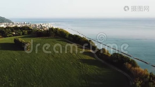 无人机在绿树山上升起，具有史诗般的海景，揭示了意大利佩索罗的小阳光镇的全景。视频