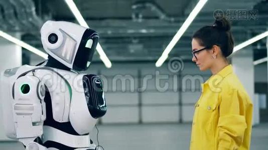 人和现代机器人触摸手，站在房间里。视频
