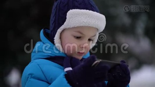 冬天的小男孩在寒冷的雪天穿手机视频