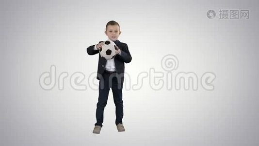 穿正式西装的男孩在梯度背景下踢足球。视频
