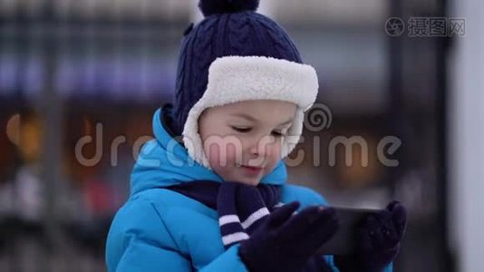 冬天的小男孩在寒冷的雪天穿手机视频