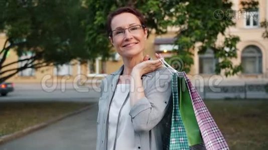 慢镜头肖像成熟女士拿着购物袋微笑在外面视频