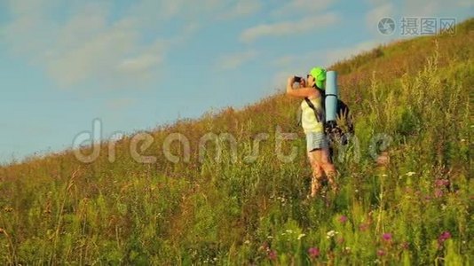 女徒步旅行者在山上，背着一个背包和望远镜在电话中拍摄大自然。视频