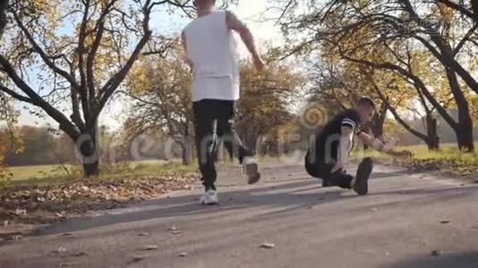 两个年轻的白人强壮的运动员在秋季公园伸展。 成年帅哥在运动前热身视频