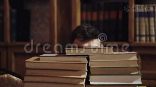 一个有趣的留胡子的人。 在图书馆的书堆之间，有着快乐面孔的人，背景上的书架。 有意思的是视频