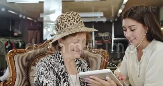 孙女和祖母听音乐，通过平板电脑在网上购物视频