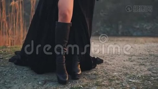 神奇湖岸上的黑暗女王，穿着别致黑色连衣裙、宽松花边袖子和高皮靴的邪恶女巫，女孩视频