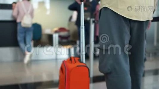 带着橙色手提箱的人在飞机起飞前排队办理登机手续。 航空旅行概念视频