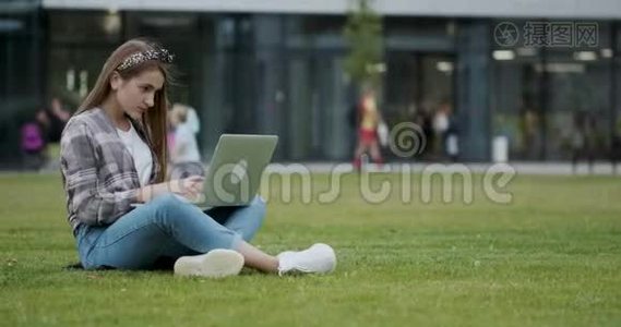 女孩用笔记本电脑在互联网上查找信息。 一个漂亮的女大学生坐在阴凉处视频