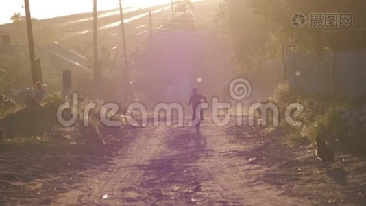 男孩骑着自行车在夕阳下沿着村庄的道路。视频