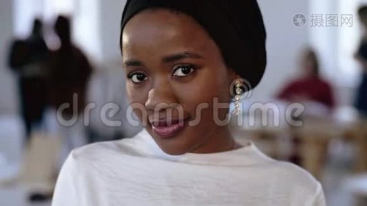 年轻快乐的非洲商务女性的特写肖像，在少数民族的头巾摆姿势，微笑在现代时尚的办公室。视频