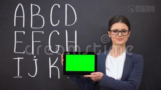微笑老师拿着预先准备好的平板电脑，黑板上的字母表，创新视频