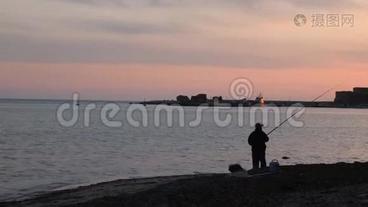 粉红色日落时人们在海上投掷鱼竿的剪影。 日落时分，渔民在海滨捕鱼视频