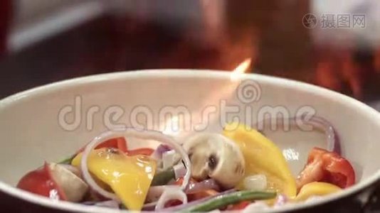 红辣椒，蘑菇和紫色洋葱在陶瓷煎锅中的火焰。 多汁蔬菜的特写视频