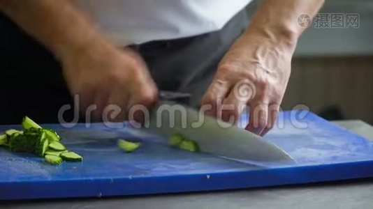 厨师把黄瓜切在蓝色的切割板上。 手的特写动作视频