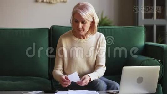 严重的成熟女人会用手提电脑计算拿着文件的账单视频