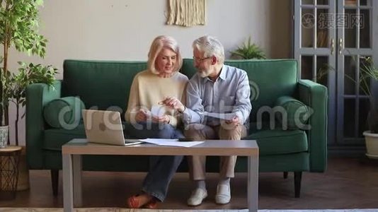 快乐的老夫妇用笔记本电脑在家里计算家庭账单视频
