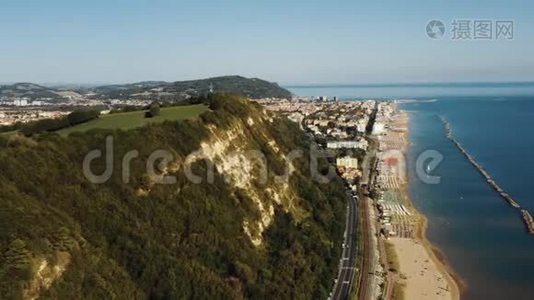 令人难以置信的空中背景全景绿色地中海海岸山，沙海海滩和小镇佩索罗。视频