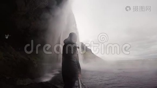 年轻的游客拿着自拍棒，在冰岛的gopro相机上拍摄强大的瀑布Seljalandsfoss。视频