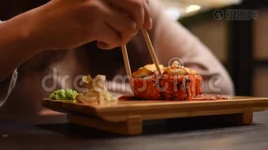 一个女孩坐在咖啡馆里，在中国或日本餐馆里有面包卷和寿司。 有筷子的漂亮女人吃烤卷视频