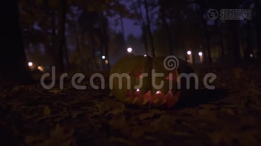 晚上秋天公园的特写镜头里，一个大南瓜，里面放着一支燃烧的蜡烛。 概念视频