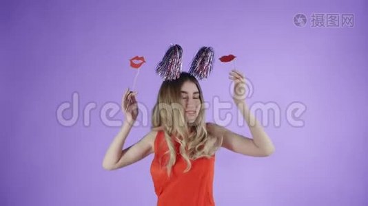 戴着派对帽的漂亮女孩在紫色背景下的肥皂泡下跳舞。视频