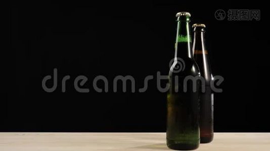 新鲜啤酒。 在木桌上放着美味的手工啤酒，放在绿色和棕色瓶子附近视频