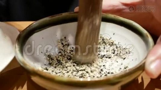 日本餐馆的女人在碗里捣碎芝麻的动作视频