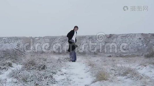 一个穿着严格的西装，穿着黑色外套的女孩走在白雪覆盖的山上视频