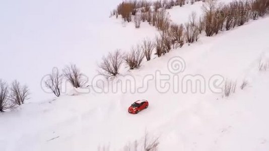 橙色的汽车正沿着一条冬天下雪的乡村道路行驶。 从无人驾驶飞机上俯瞰。视频