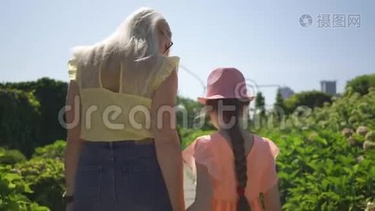 后景金发母亲与女儿在夏园牵手散步.. 家庭幸福，单亲家庭。 连接视频