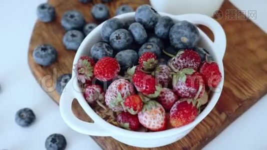 用草莓和蓝莓做成的碗放在带有牛奶的木切割板上视频