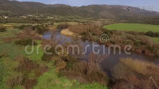 在撒丁岛上空盘旋的湖泊和科希纳斯河的鸟瞰图，环绕着树木和农田。视频