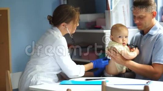 父亲和他的孩子在儿科医生`约会。 一位女医生检查一个一岁半的小男孩视频