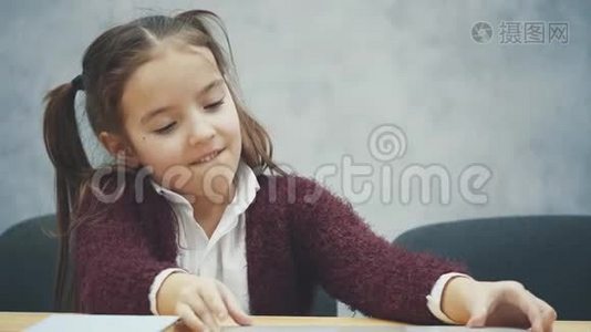 快乐可爱的聪明女孩坐在桌子上的一叠书和笔记本电脑的肖像，复制空间。 教育与发展视频