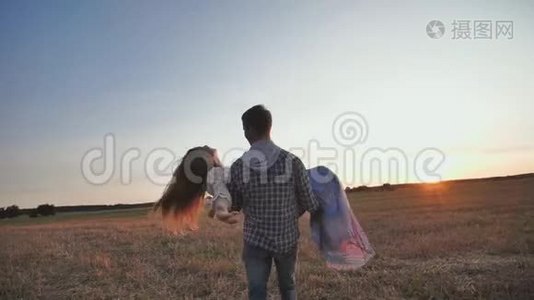 一个男人在夕阳背景下抱着女友转圈。视频