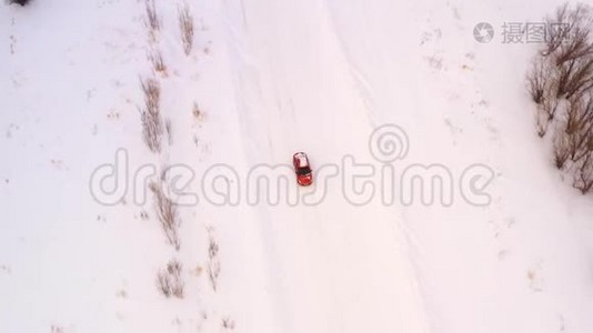 橙色的汽车正沿着一条冬天下雪的乡村道路行驶。 从无人驾驶飞机上俯瞰。视频