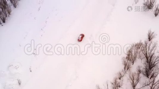 橙色的汽车正沿着一条冬天下雪的乡村道路行驶。 从无人驾驶飞机上俯瞰。视频