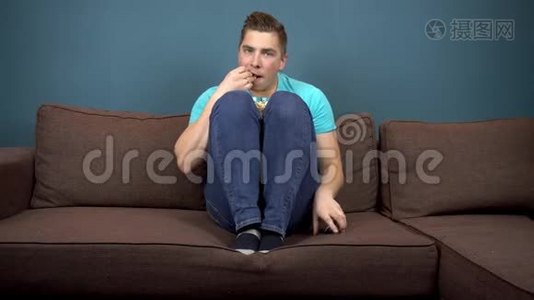 一个年轻人正在看电视和吃爆米花。 那家伙正在仔细看电视。 一个激动人心的时刻视频