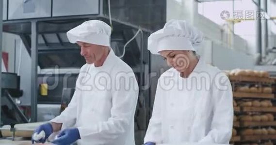 美丽迷人的三个面包师一起工作在一个烘焙行业，形成面团烘焙面包视频