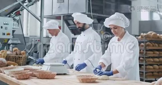 非常有魅力的面包师女人带着大大的微笑，她的同事则是面包师们在面团中烘烤面包视频