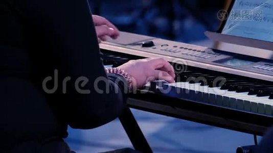 女性双手在七彩舞台灯光下弹电钢琴，特写.. 音乐家妇女在键盘上表演作曲视频