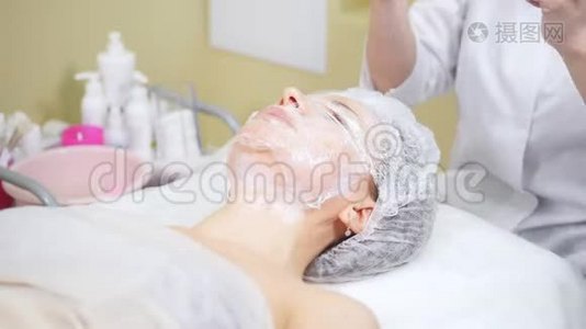 美容师包装在电影客户`的下巴做美容程序清洗脸在美容诊所。视频