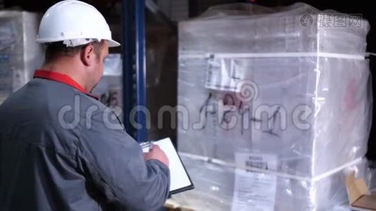 一个戴着头盔的仓库工人把他的笔记写在他的文件夹里。 4K慢慢视频