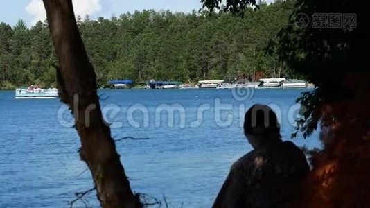 明尼苏达州的湖景，一艘浮舟接近岸边，树干和一个人的轮廓。视频