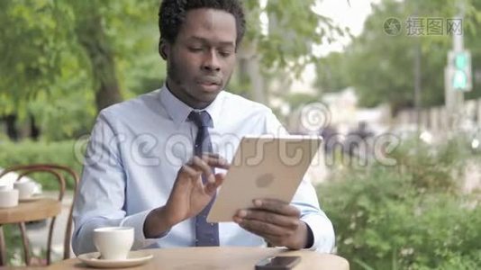 非洲商人坐在户外咖啡厅，坐在桌上因损失而心烦意乱视频
