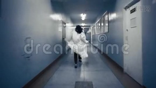 穿着白色外套的女人沿着一条黑暗的走廊跑，从后面看。视频